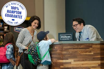 Man at front desk smiling at a child next to his mother